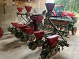 un tracteur rouge garé à côté d'une rangée de semoirs rouges