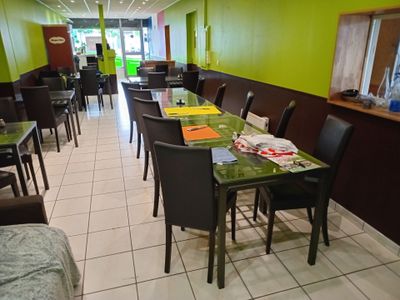 tables and chairs in a restaurant with green walls and white tile floor