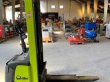 a forklift in a warehouse with pallets in the foreground