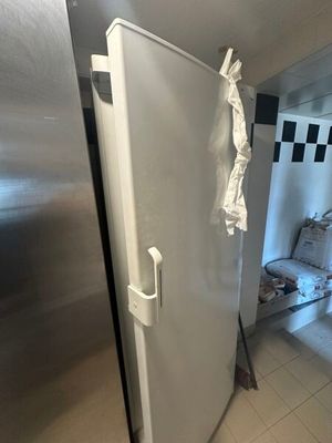un réfrigérateur blanc dans un coin d'une pièce dont le mur est à carreaux noirs et blancs