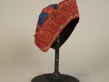 un chapeau rouge et bleu posé sur un socle noir