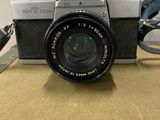 a silver camera with a black lens and a pair of glasses