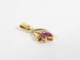 a close up of a gold pendant with a pink stone