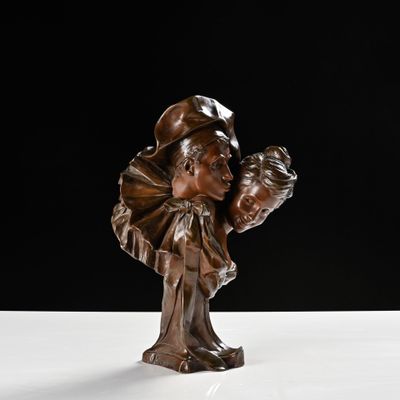 statue en bronze représentant une femme tenant un enfant dans ses bras, posée sur une surface blanche