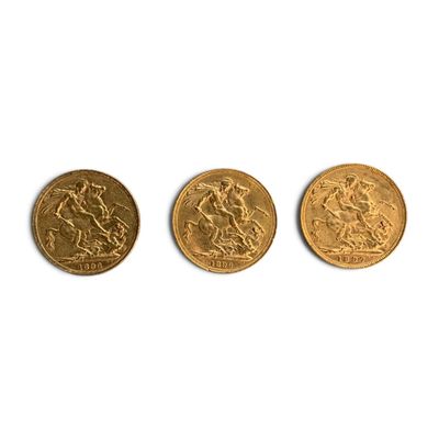 trois pièces d'or sont alignées sur une surface blanche