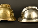 pair of silver and gold fire helmets on a black background