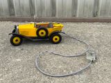 un petit camion jaune auquel est fixé un tuyau