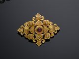 a close up of a gold broochle on a black surface