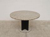 a round table with a black base on a concrete floor