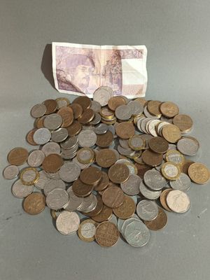une pile de pièces posée sur une table à côté d'un billet de banque