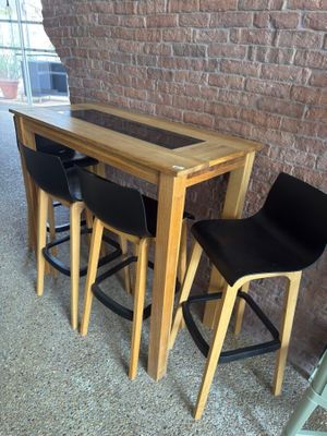 three black chairs sitting at a table with a wooden table top