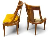 two wooden chairs with yellow upholstered cushions on a white background