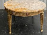 a marble top table with gold legs on a black floor