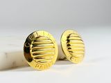 pair of gold tone cufflinks on a white marble surface
