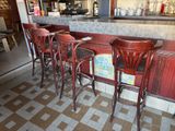 four wooden chairs sitting at a bar with a checkered floor