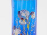 un vase bleu orné de fleurs, posé sur une surface blanche