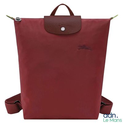 a red backpack with a brown handle and a brown strap