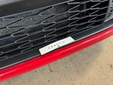 a close up of the grille of a red car with a sticker on it