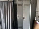 two lockers in a room with a fan in the corner