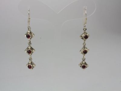 a pair of silver earrings with garnets on them