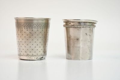 deux tasses en argent posées l'une à côté de l'autre sur une table