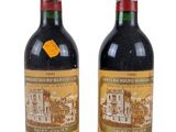 two bottles of red wine sitting next to each other on a white surface