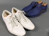 two pairs of white shoes are lined up on a gray surface