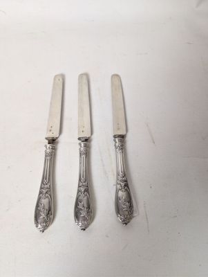 three forks and a knife on a table with a white table cloth