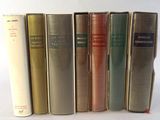 several books are lined up in a row on a white surface