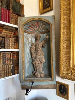 a statue of a man on a shelf in a room full of books