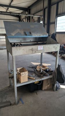 un établi métallique sur lequel est posé un ordinateur portable, dans un entrepôt