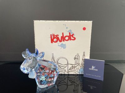 une figurine de vache en verre posée sur une table, à côté d'une boîte de bonbons