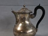 an antique silver coffee pot with a black handle on a white background
