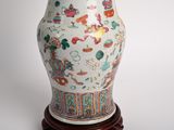 a white vase with colorful designs on it on a wooden stand