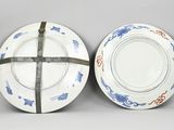 two blue and white plates with designs on them on a gray surface