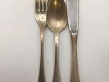 three forks and a knife on a white table