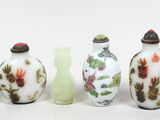 cinq vases en verre posés les uns à côté des autres sur une surface blanche