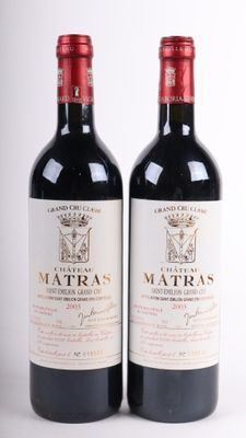 deux bouteilles de vin rouge posées l'une à côté de l'autre sur une surface blanche