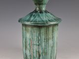 a green vase with a lid sitting on a table