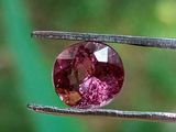 un gros plan d'un diamant rose tenu par une paire de pinces