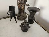a statue of a woman holding a bird next to two cups and a vase
