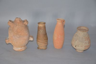 quatre vases en argile sont alignés sur une surface grise