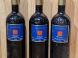 three bottles of wine sit on a wooden shelf in front of a wooden wall