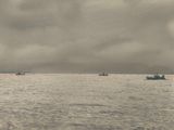 many boats that are out in the ocean on a cloudy day