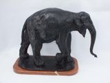statue of an elephant standing on a wooden base on a white background
