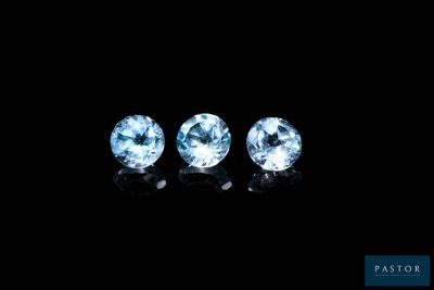 three blue topaz gems on a black background