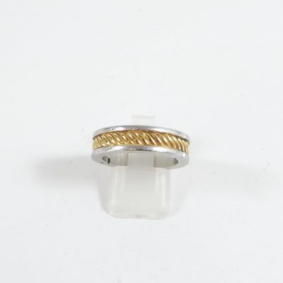 un gros plan d'une bague en argent et en or posée sur une surface blanche