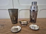 a lot of silver items on a table next to a shaker