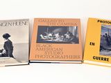 Trois livres sont posés sur une surface blanche ; l'un est une photographie et l'autre est une photographie.