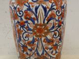 un vase bleu et orange posé sur une surface blanche